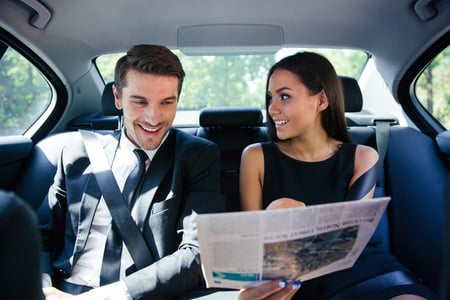 Happy couple reading newspaper in car